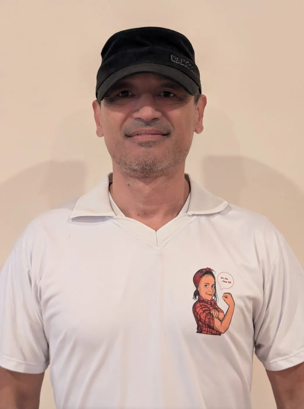 DA Maids crew member in a black cap and white polo with the mascot crest